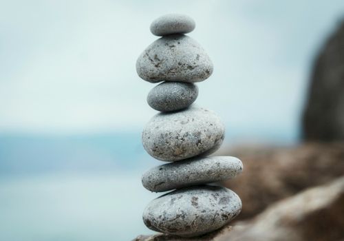 Stacked smooth stones balanced on a rocky shore, creating a tranquil zen cairn by the water.