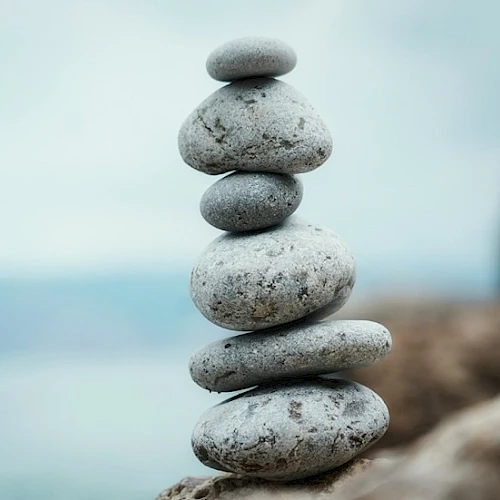 Stacked smooth stones balanced on a rocky shore, creating a tranquil zen cairn by the water.