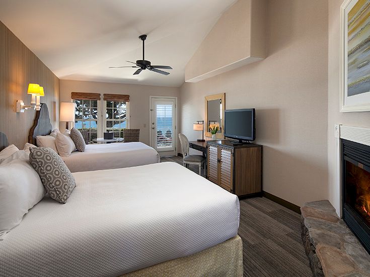 A hotel-style room with two beds, a fireplace, flat-screen TV, desk, and a balcony outside. 140 characters, ending with a period.