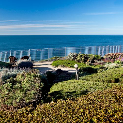A rocky coastline with grassy shore, calm blue sea, and clear sky, sunny and tranquil.