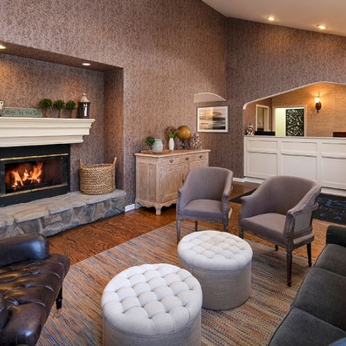 A cozy, modern living room with a large sectional sofa, round coffee tables, warm lighting, and a flat-screen TV.