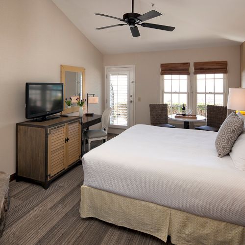 A cozy bedroom with a low-profile bed, nightstands, warm lighting, a seating area, a fireplace, and minimalist decor.